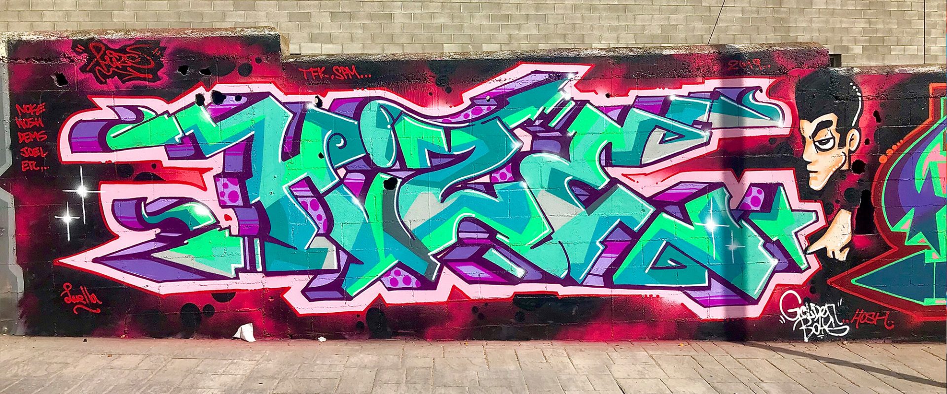 Hize graffiti mural with turquoise lettering and portrait character on a long wall